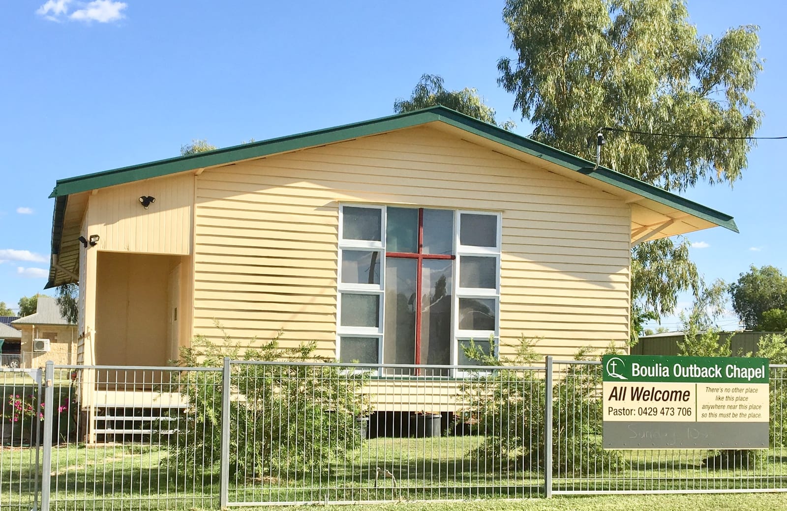 The Boulia Outback Chapel building, a small church with a cross-shaped window and a sign reading 'All Welcome'